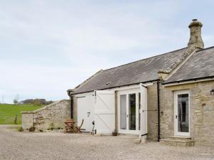 an old stone cottage with a white garage at The Coach House in Whittingham