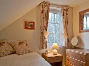 een slaapkamer met een bed en een raam bij Edenwoodend Cottage in Kilmaron