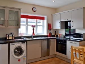 a kitchen with white cabinets and a washer and sink at The Willows in Toynton All Saints
