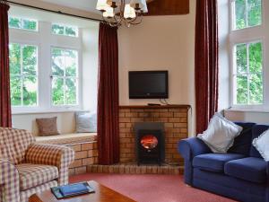 a living room with a fireplace and a tv at Kennedy Cottage in Straiton