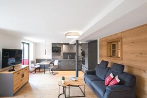 sala de estar con sofá azul y cocina en Chalet-Ferienwohnung Kornspeicher, 70 qm, Wellness/Fitness/Sauna – Bergrödelhof, en Feilitzsch