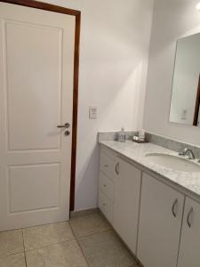 baño con lavabo y puerta con espejo en Condominio de Paz en Tandil