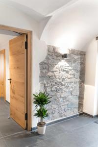 una planta en una habitación con una pared de piedra en Chalet-Ferienwohnung Kornspeicher, 70 qm, Wellness/Fitness/Sauna – Bergrödelhof, en Feilitzsch