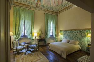 a bedroom with a bed and a table and two windows at Palazzo Carletti in Montepulciano