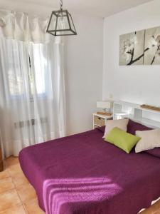 a purple bed in a white room with a window at La bastide neuve - le cabanon in La Môle