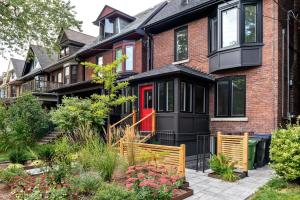 a brick house with a red door and a garden at Stunning TreeTop Views at HighParkHomes dot ca in Toronto