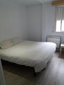un grand lit blanc dans une chambre avec une fenêtre dans l'établissement Príncipe habitaciones, à Madrid