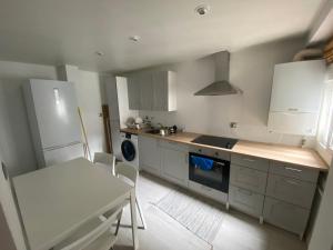 une cuisine avec des armoires blanches, une table et une cuisinière dans l'établissement Príncipe habitaciones, à Madrid