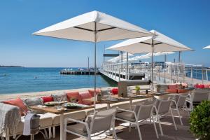 a restaurant with tables and chairs on the beach at Hôtel Barrière Le Majestic Cannes in Cannes
