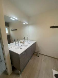 ein Badezimmer mit zwei Waschbecken und einem großen Spiegel in der Unterkunft Maison bord de mer Chez JuJu in Grandcamp-Maisy