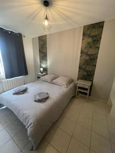 ein Schlafzimmer mit einem Bett mit einer Lampe und einem Tisch in der Unterkunft Maison bord de mer Chez JuJu in Grandcamp-Maisy