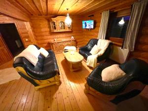 a living room with leather furniture in a log cabin at TRINITY Log Cabin Wellness resort in Štrba