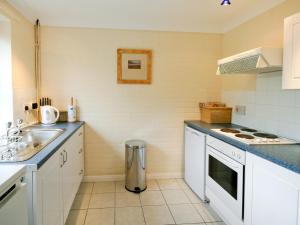 a kitchen with white cabinets and a sink and a stove at Lindas Lodge in Holton