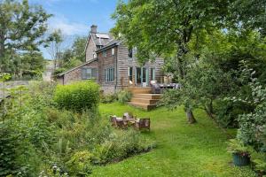 una casa con un patio con bancos delante en Luxury Cottage near Hay-on-Wye, en Llanigon