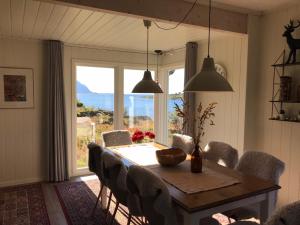 a dining room with a table and chairs and a large window at Sundklakk Feriehus i Lofoten in Sundklakk