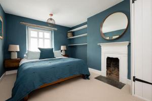 ein blaues Schlafzimmer mit einem Bett und einem Spiegel in der Unterkunft Luxury Cottage near Hay-on-Wye in Llanigon