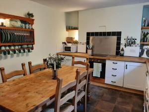 a kitchen with a wooden table with chairs and a kitchen with a refrigerator at Selah Teifi spectacular river view with games room in Llandysul