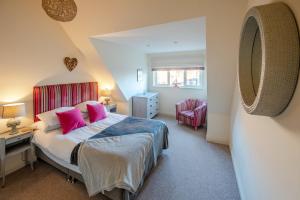1 dormitorio con 1 cama grande con almohadas rosas en The Pilchard by Big Skies Cottages en Wells next the Sea