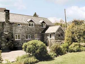 an old stone house with a wooden gate in a yard at The Old Mill in Bampton