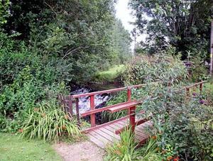 uma ponte de madeira no meio de um jardim em The Old Mill em Bampton