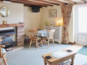 a living room with a table and a fireplace at Pegg Inn Cottage in Allgreave