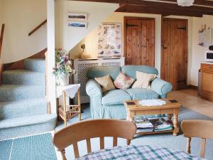 a living room with a blue couch and a table at Pegg Inn Cottage in Allgreave