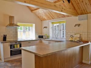 a large kitchen with wooden ceilings and a large counter top at Bowles Cottage in Lechlade