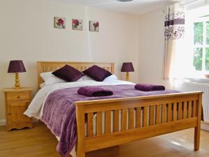 a bedroom with a large bed with purple blankets at Bowles Cottage in Lechlade