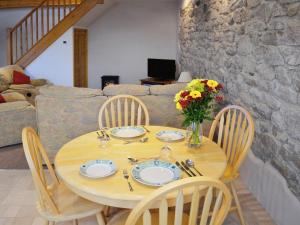 una mesa de madera con platos y un jarrón de flores en The Old Coach House en St Austell