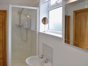 a bathroom with a sink and a shower and a mirror at The Old Coach House in St Austell
