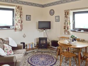 a living room with a couch and a table and a tv at Harebell Hill Jericho Farm in Earl Sterndale