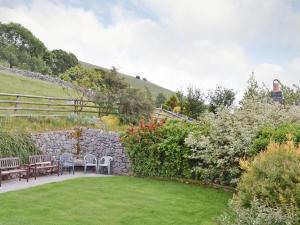 a garden with two benches and a stone wall at Harebell Hill Jericho Farm in Earl Sterndale