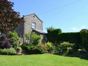 an old stone house with a garden in the foreground at Primrose Cottage - Lpg in Ireby