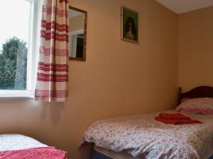1 Schlafzimmer mit 2 Betten, einem Spiegel und einem Fenster in der Unterkunft Broadstone Cottage in Norham