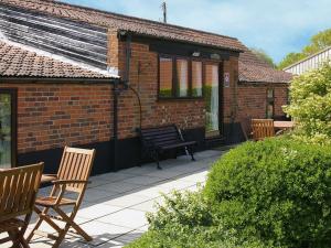 ein Backsteinhaus mit Stühlen und einer Bank auf einer Terrasse in der Unterkunft Stiff Key Barn 30955 in Thursford