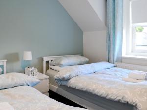 1 dormitorio con 2 camas y ventana en Dovecote House, en Wooler