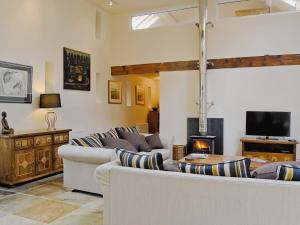 a living room with couches and a tv and a fireplace at Hendre Barn Mawr in Abergynolwyn