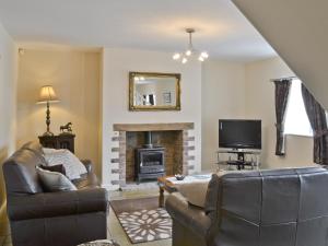 a living room with a couch and a fireplace at John Wesley Cottage in West Kyo