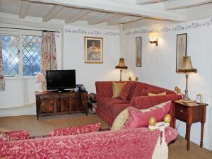 a living room with red couches and a tv at Hathaway Hamlet in Stratford-upon-Avon