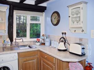 a kitchen with a sink and a clock on the wall at Hathaway Hamlet in Stratford-upon-Avon