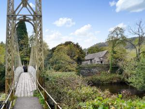 un puente sobre un río con gente caminando sobre él en Smithy House en Betws-y-coed