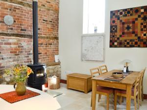 uma sala de estar com uma mesa e um fogão a lenha em The Barn Reborn - Nrp em Winchcombe