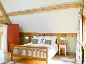 a bedroom with a large white bed and a bench at The Barn Reborn - Nrp in Winchcombe
