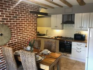 een keuken met een houten tafel en een bakstenen muur bij Mill Stone Cottage in Wolsingham
