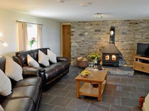a living room with a leather couch and a fireplace at Golygfar Mynydd - Mountain View in Strata Florida
