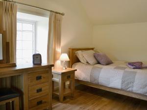 a bedroom with a bed and a dresser and a window at Golygfar Mynydd - Mountain View in Strata Florida
