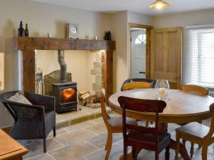a dining room with a table and a wood stove at West End Cottage in Whittingham