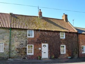 an old brick building with a white door at West End Cottage in Whittingham
