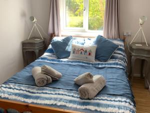 a bed with towels on it with a window at Sandpipers in Pyworthy