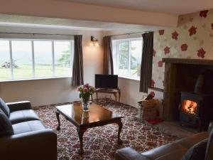 a living room with a table and a fireplace at Blackhill Gate Cottage in Taxal